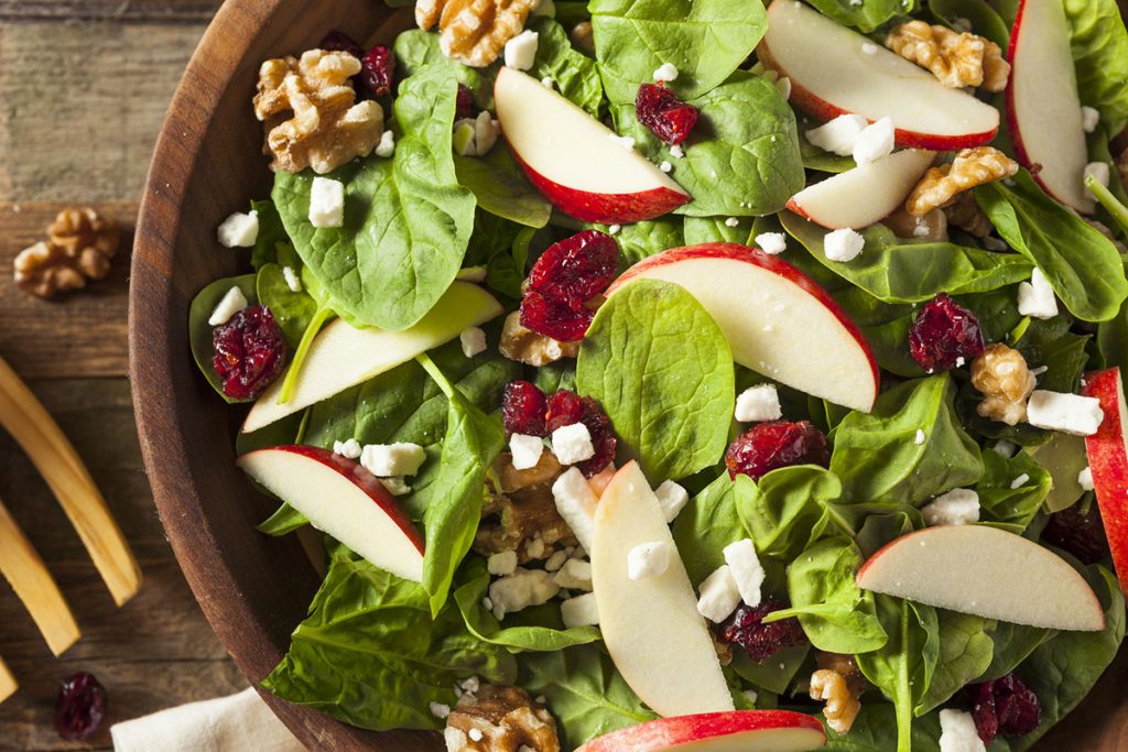 Homemade Fresh Salad with Spinach, Walnuts, and Apples in a Wooden Bowl